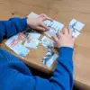 Kinderhände, die ein ausgedrucktes Puzzle-Bild zusammenfügen